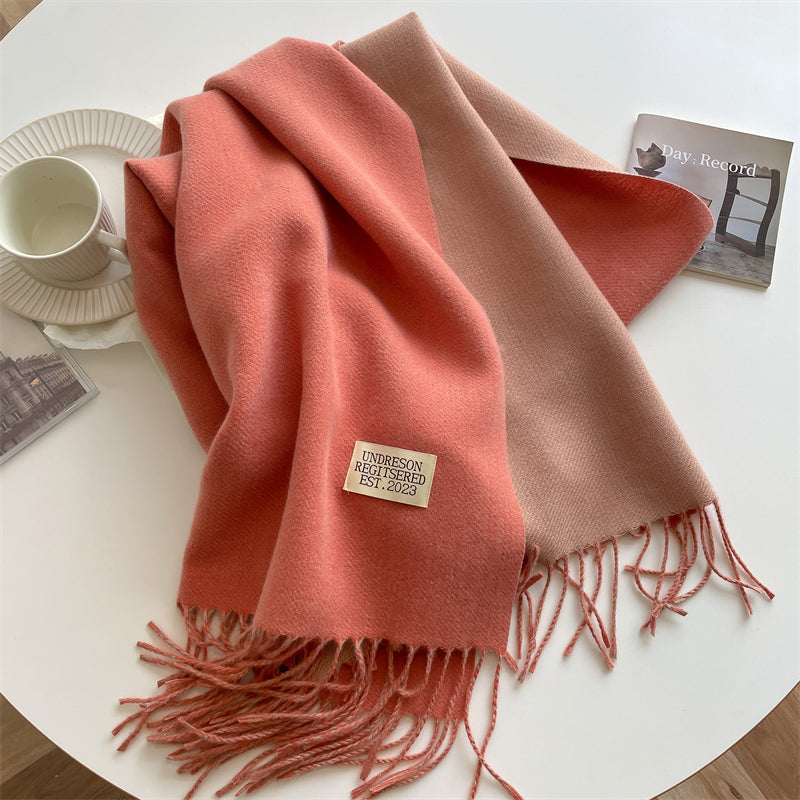 Rosa und beige Wollschal mit Fransen auf Tisch, Kaffeetasse, Tageslicht, gemütlich, modisch.