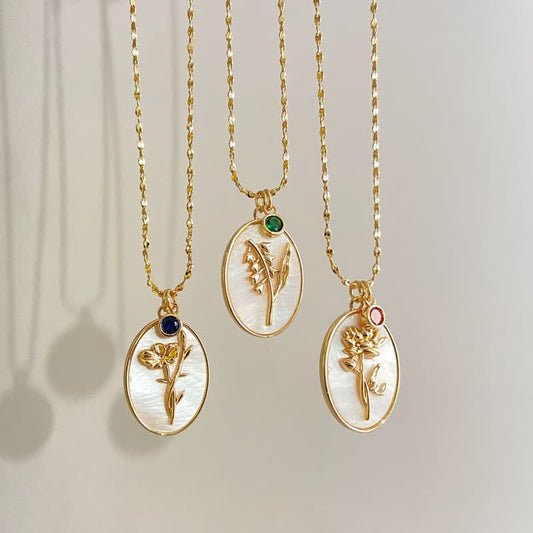 Drei goldene Halsketten mit Blumenanhängern, Perlmutt und Edelsteinen, eleganter Schmuck.