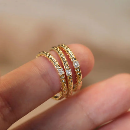 Drei goldene Ringe mit Diamanten, filigran, stapelbar, Schmuck für Damen, elegantes Design.