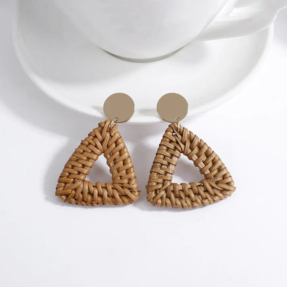 Dreieckige Ohrringe aus geflochtenem Rattan, goldene Details, modisches Accessoire.