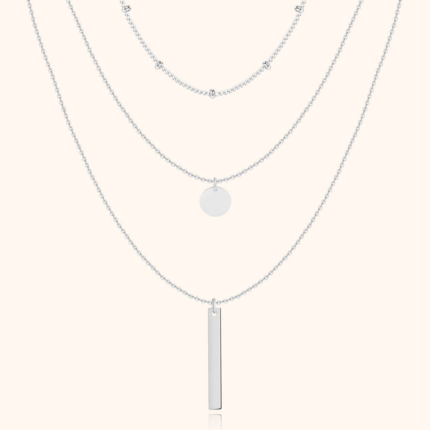 Silberne Halskette mit drei Lagen, Anhänger und Kugeldetails, eleganter Schmuck für Damen.