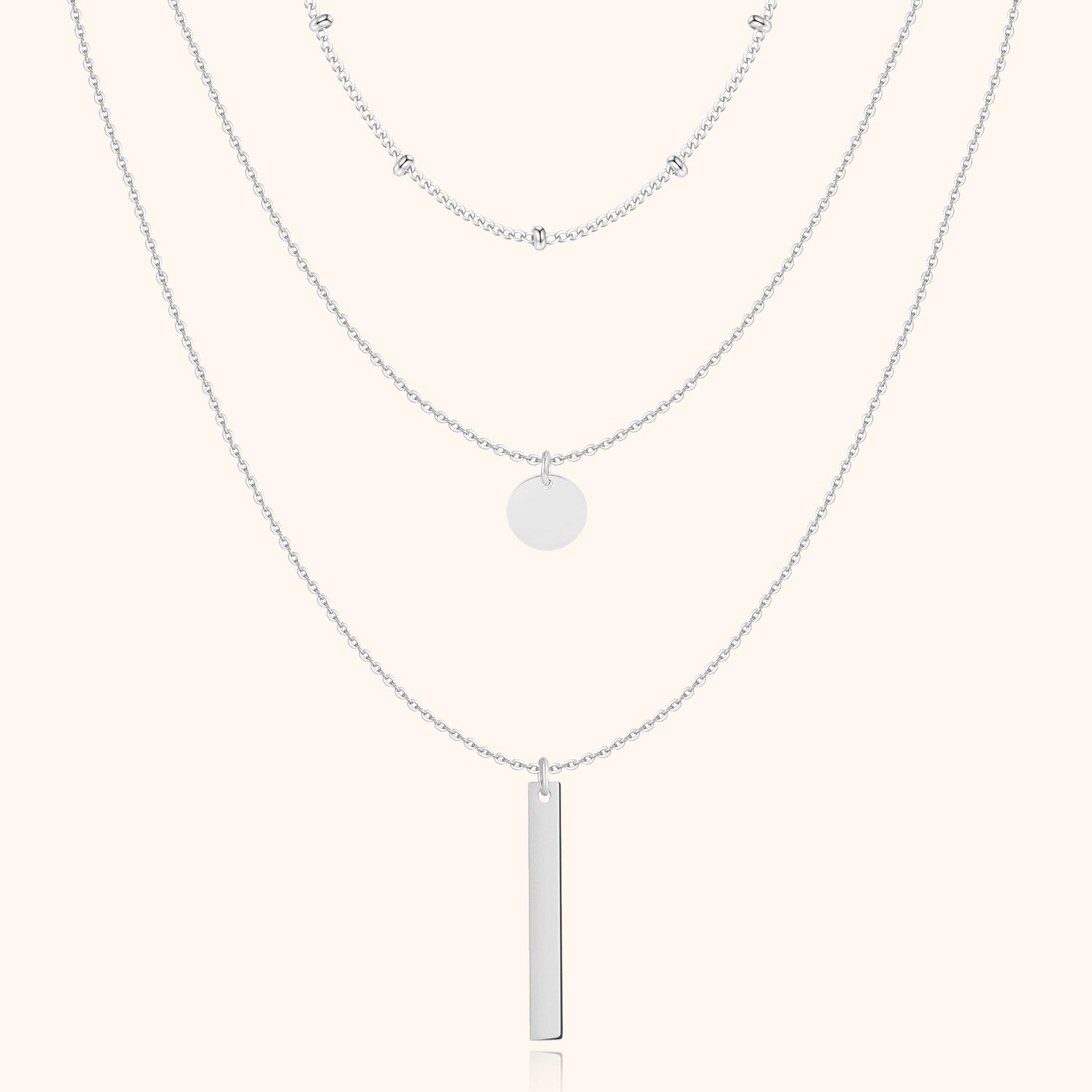 Silberne Halskette mit drei Lagen, Anhänger und Kugeldetails, eleganter Schmuck für Damen.