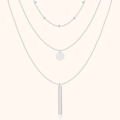 Silberne Halskette mit drei Lagen, Anhänger und Kugeldetails, eleganter Schmuck für Damen.