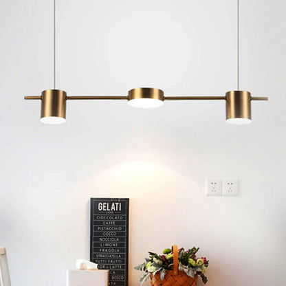 Moderne dreiflammige Pendelleuchte aus Messing über Esstisch, minimalistisch, stilvoll.