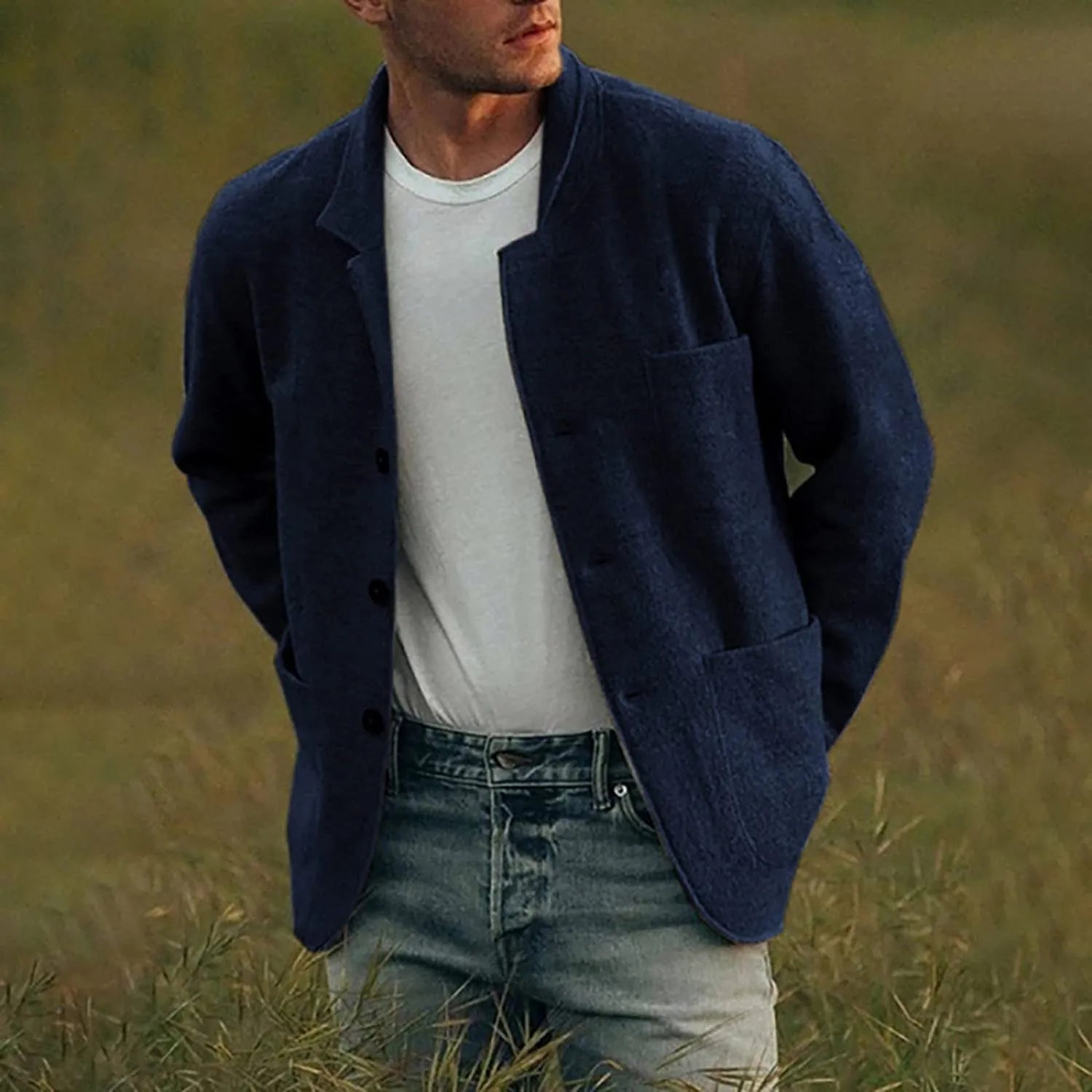Mann in dunkelblauem Sakko und weißem T-Shirt, lässiger Stil, Outdoor-Hintergrund.