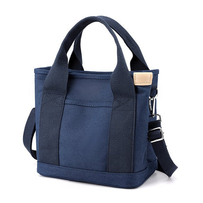 Dunkelblaue Canvas-Tasche mit Tragegriffen und Schulterriemen, modisch und praktisch.