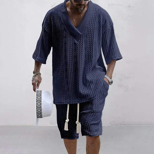 Mann in dunkelblauem Strickset, V-Ausschnitt, kurze Ärmel, Sommermode, lässiger Stil.