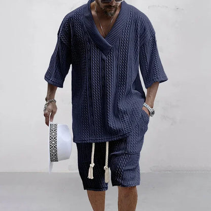 Mann in dunkelblauem Strickset, V-Ausschnitt, kurze Ärmel, Sommermode, lässiger Stil.