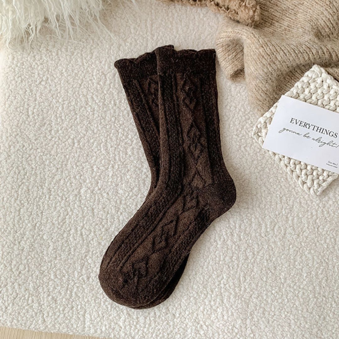Braune Stricksocken mit Zopfmuster auf beigem Hintergrund, gemütliche Wintermode Accessoire.