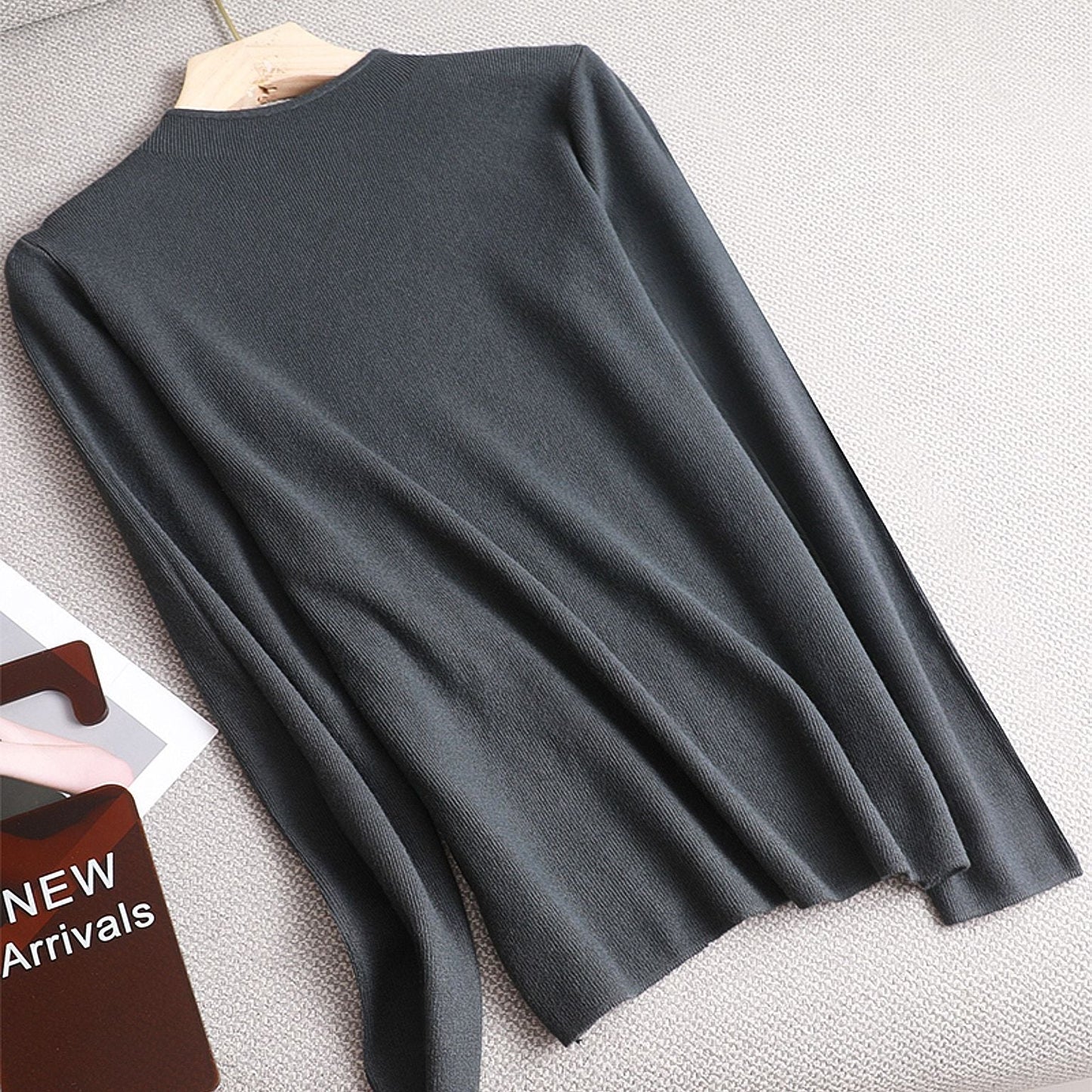 Dunkelgrauer Strickpullover aus Baumwolle, langärmelig, auf Kleiderbügel, neue Kollektion.