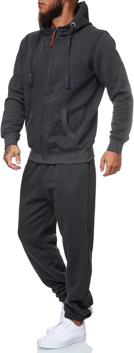 Mann in dunkelgrauem Jogginganzug mit Kapuze, Reißverschluss und weißen Turnschuhen.