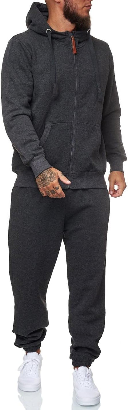 Mann in dunkelgrauem Kapuzenpullover und Jogginghose, weiße Sneaker, Freizeitmode.