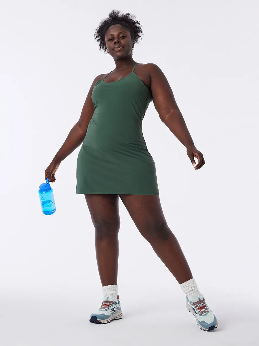 Frau in grünem Sportkleid mit Wasserflasche, Turnschuhe, Fitnessmode, bequem, atmungsaktiv.