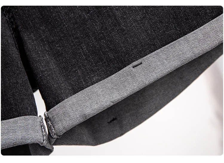 Dunkelgraue Jeansstoff-Detailaufnahme, umgeschlagener Saum, hochwertige Denim-Textur.