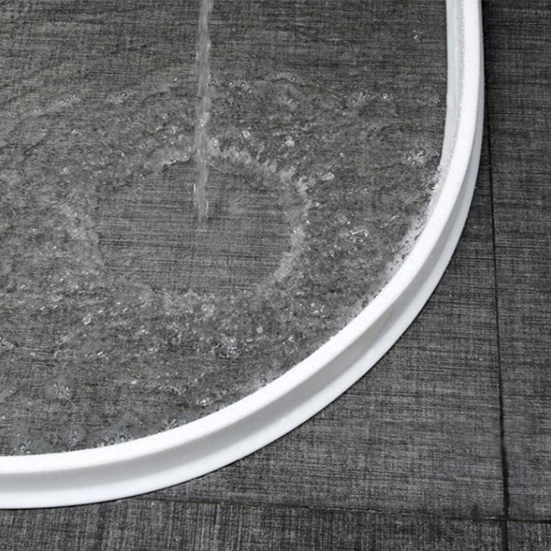 Weiße Duschwanne mit Wasserstrahl, graue Fliesen, modernes Badezimmerdesign.