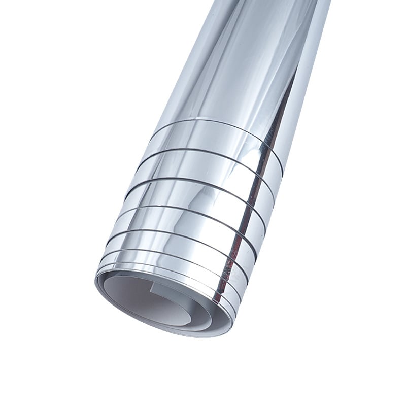 Silverfärgad rullad spegelfilm mot vit bakgrund, med den vita baksidan synlig i rullens ände 1