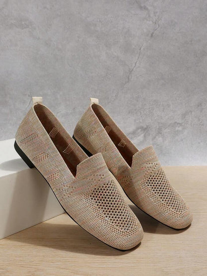 Ett par beige mesh-skor med genombrutet mönster lutade mot en vit låda, med dragflik bak, mot en grå väggbakgrund. 7