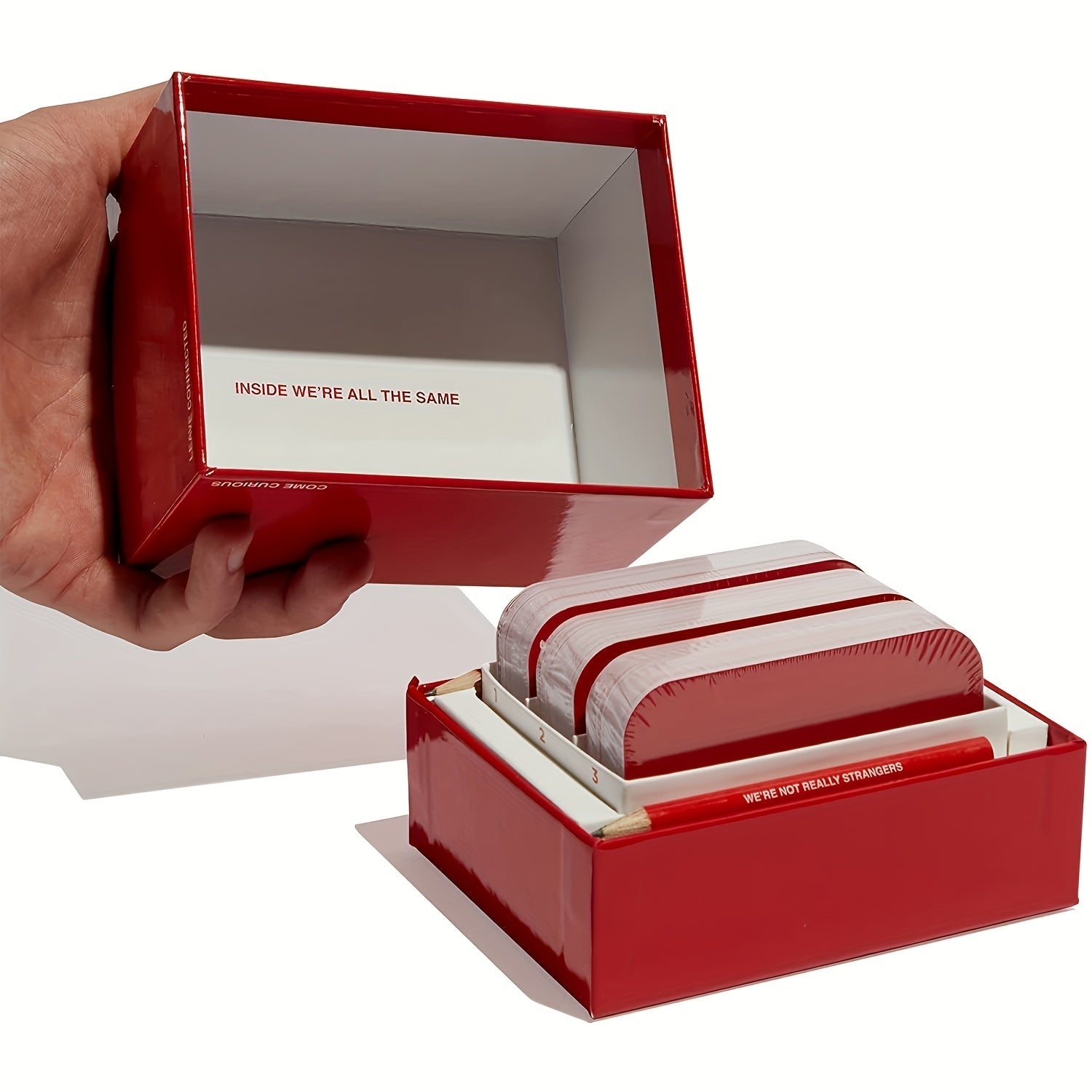 Rotes Kartenspiel-Set "We're Not Really Strangers" in offener Box, Hand hält Deckel.