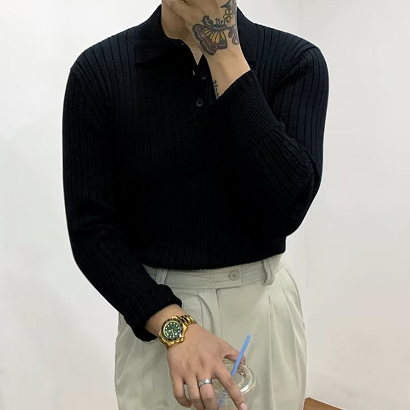 Mann in schwarzem Strickpullover, beige Hose, hält Getränk, trägt goldene Uhr, tätowierter Arm.