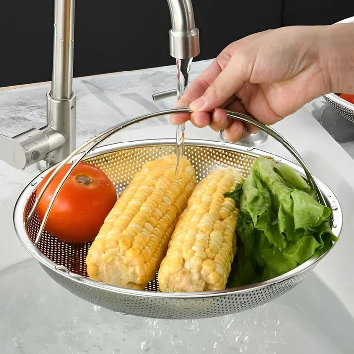 Hand wäscht Gemüse in Edelstahl-Sieb: Tomate, Maiskolben, Salat unter Wasserhahn.
