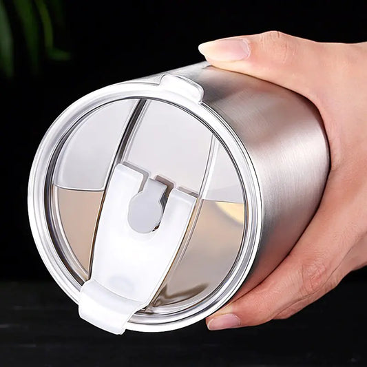 Hand hält silbernen Edelstahl-Thermobecher mit Deckel, isoliert, wiederverwendbar, umweltfreundlich.