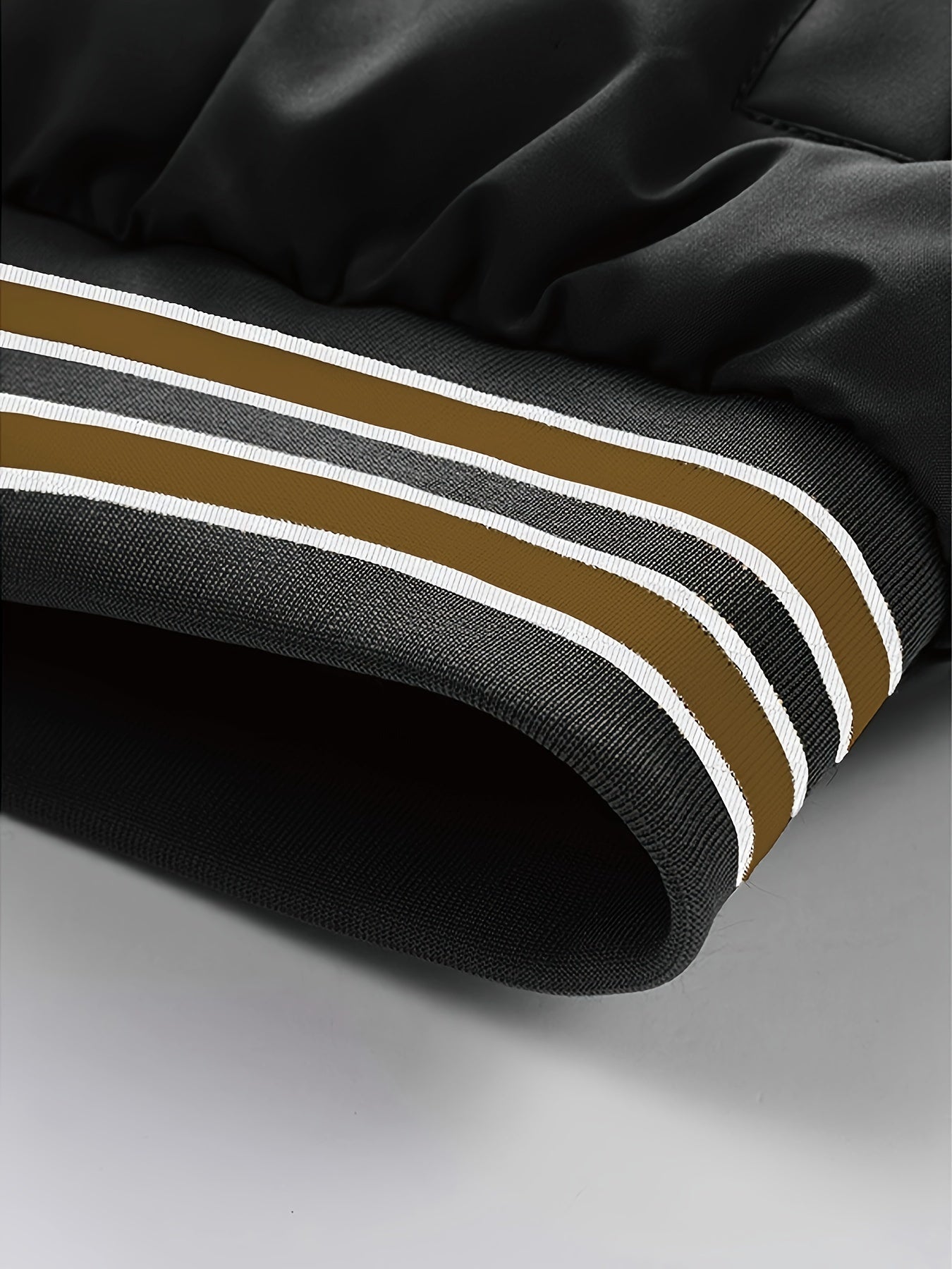 Schwarze Jacke mit braunen und weißen Streifen, modisch, Detailansicht, Polyester.