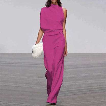 Frau in eleganter, ärmelloser, pinker Jumpsuit mit weitem Bein, hält weiße Clutch.