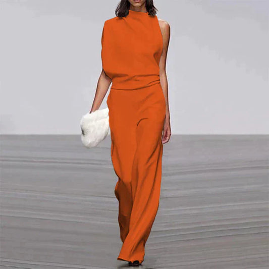 Frau in orangefarbenem, ärmellosem Jumpsuit mit weitem Bein, hält weiße Clutch, Sommermode.