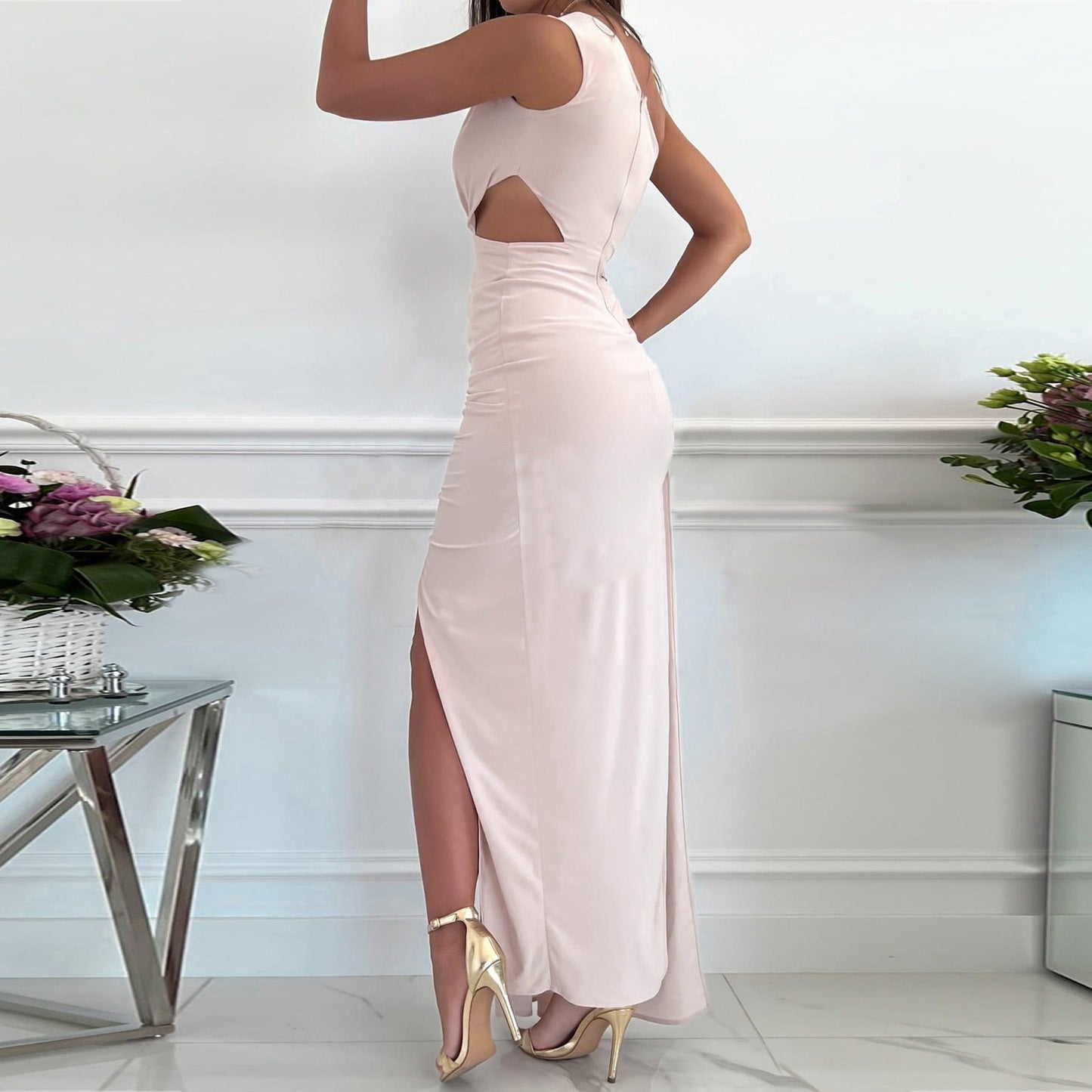 Frau in elegantem, langem, rosa Abendkleid mit Seitenschlitz und goldenen High Heels.
