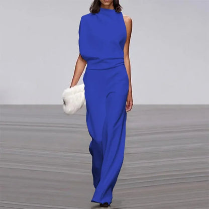 Frau in blauem Ein-Schulter-Jumpsuit mit weißer Fell-Clutch auf Laufsteg.