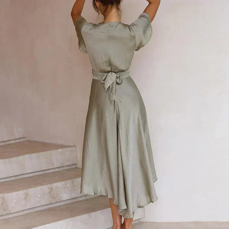 Frau in grünem Sommerkleid mit Rückenausschnitt, knielang, aus leichtem Stoff, elegant.