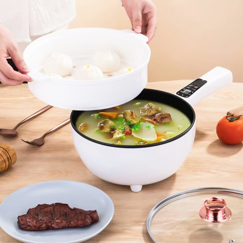 Elektrischer weißer Kochtopf mit Dampfgarer, Gemüse und Fleisch, auf Holztisch.