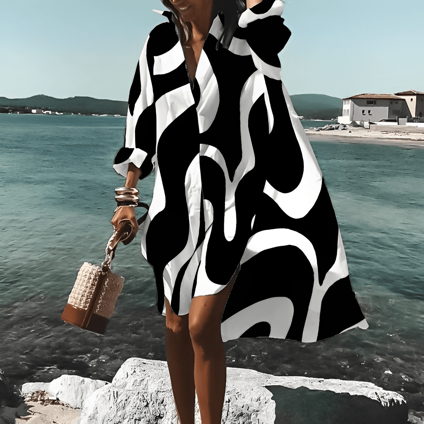 Frau in schwarz-weißem, knielangem Print-Kleid am Strand, Sommermode, stilvoll.