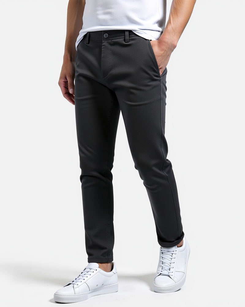 Mörkgrå slim fit-byxor snett framifrån på en modell med vit t-shirt, vita sneakers och uppvikta byxben. 12