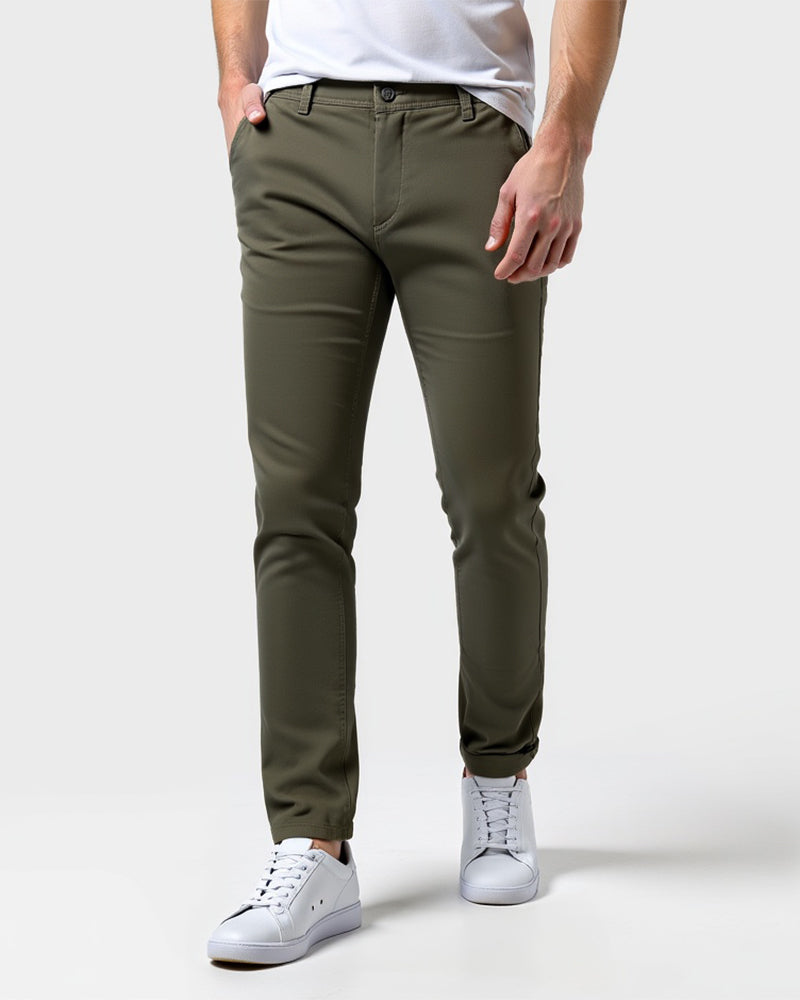 Olivgröna chinos framifrån på en modell med vit t-shirt och vita sneakers, ena handen i fickan. 13