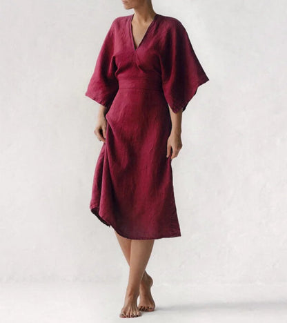 Frau in rotem Leinenkleid, knielang, mit weiten Ärmeln, minimalistisches Design.