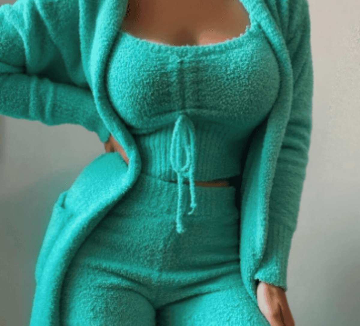 Frau in türkisfarbenem Fleece-Set, bestehend aus Crop-Top, Hose und Cardigan, modisch, bequem.