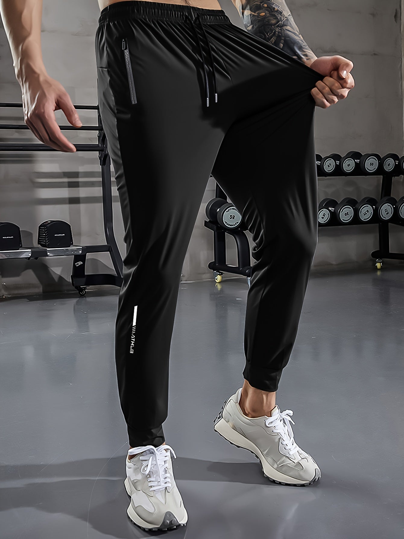 Schwarze Herren-Trainingshose, elastisch, mit Reißverschlusstaschen, im Fitnessstudio.