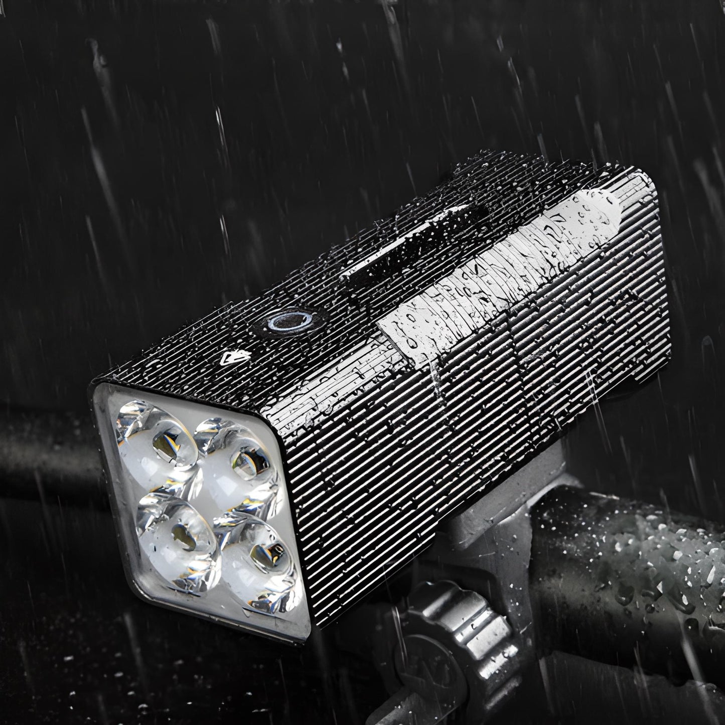 Wasserdichte LED-Fahrradleuchte, schwarz, mit vier Linsen, montiert auf Lenker, bei Regen.