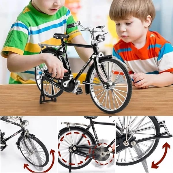 Zwei Kinder spielen mit einem schwarzen Miniaturfahrradmodell auf einem Holztisch.