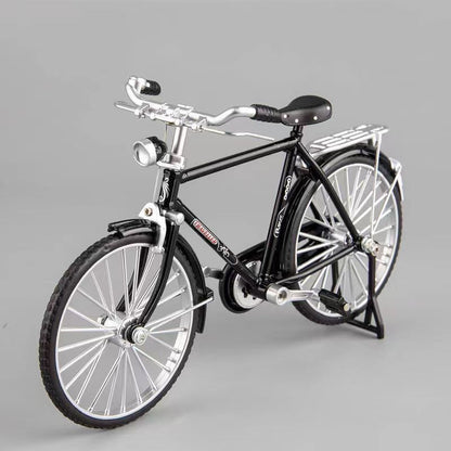 Schwarzes Miniatur-Fahrradmodell aus Metall, detailgetreu, auf grauem Hintergrund.