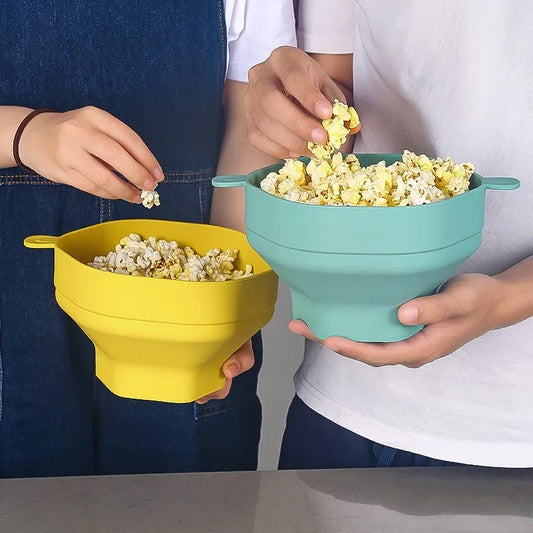 Zwei faltbare Silikon-Popcornschalen, gelb und blau, mit Popcorn, in der Küche.