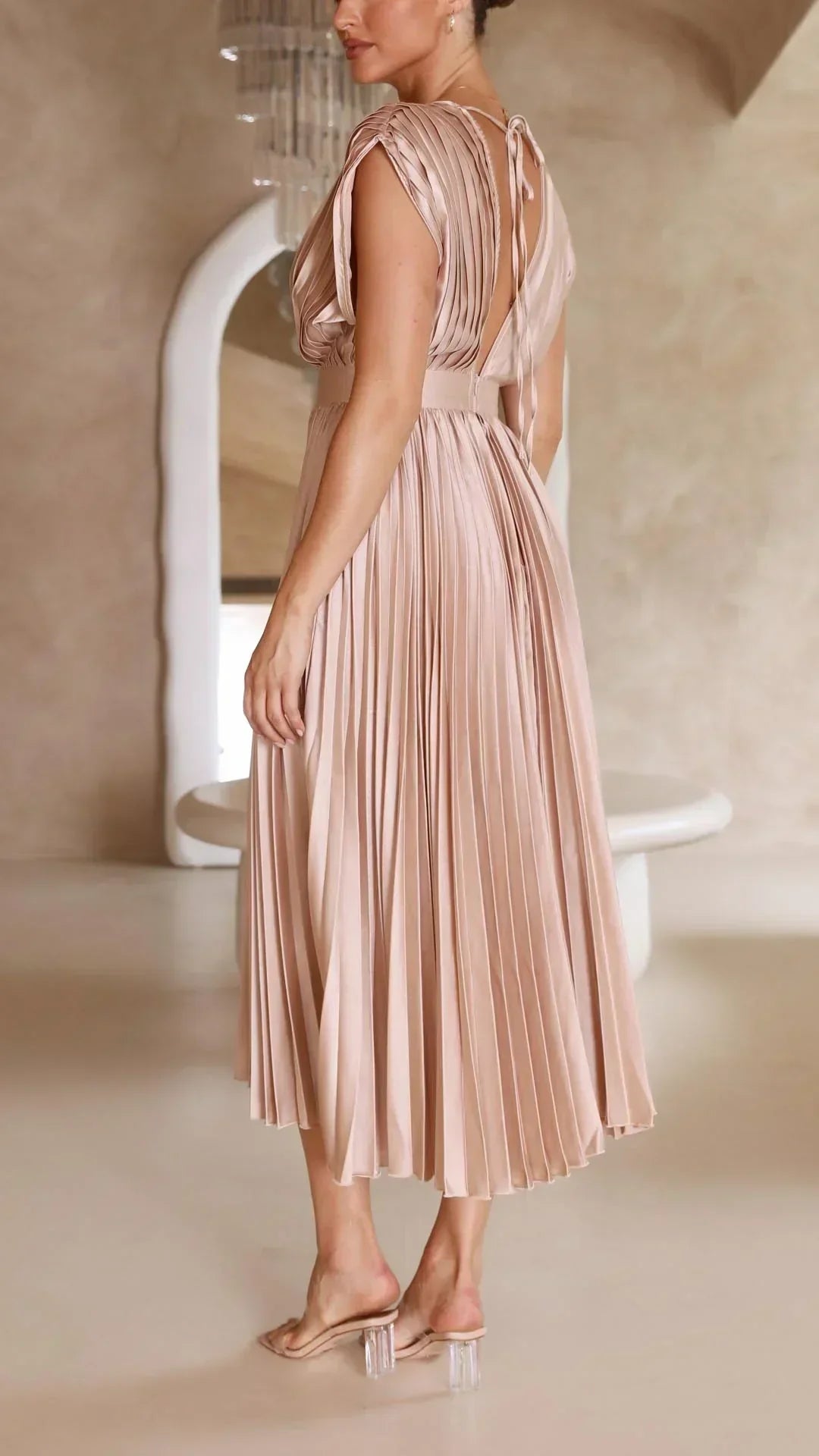 Frau in champagnerfarbenem, plissiertem Kleid aus Satin, elegantes Abendmode-Design.