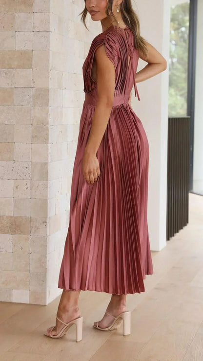Frau in rosa plissiertem Midikleid, elegantes Design, Sommermode, Innenaufnahme.