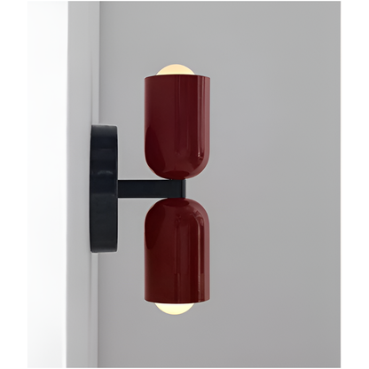 Sidovy av vägglampa med två rödbruna lampskärmar och svart arm som visar hur lampan sticker ut från väggen, med tända glödlampor. 17