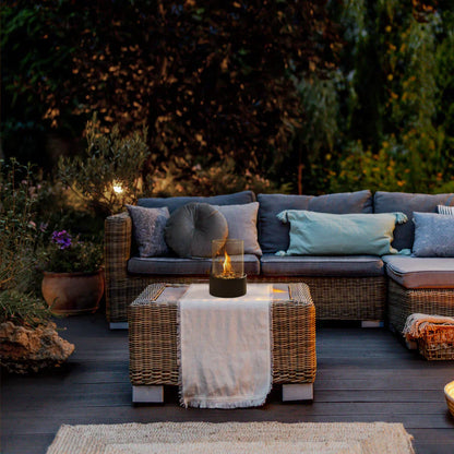 Rattan-Sofa-Set mit Kissen auf Holzterrasse, Gartenbeleuchtung, gemütliche Outdoor-Einrichtung.
