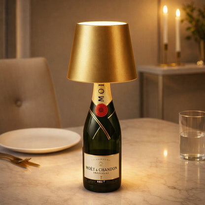 Guldfärgad flasklampa på en champagneflaska på ett marmorbord med tallrik, bestick, glas och levande ljus 17