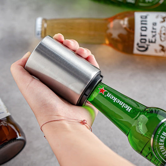 Hand hält Edelstahl-Flaschenöffner auf Heineken-Flasche, Corona-Flaschen im Hintergrund.