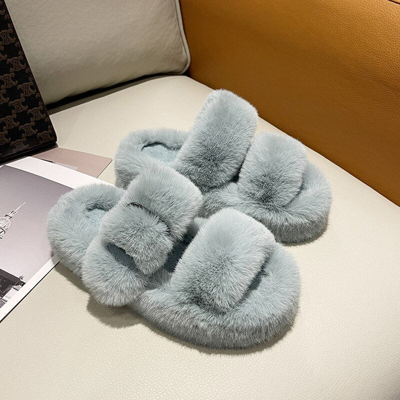 Graue flauschige Hausschuhe aus Kunstfell auf Sofa, gemütlich, modisch, Damenmode.