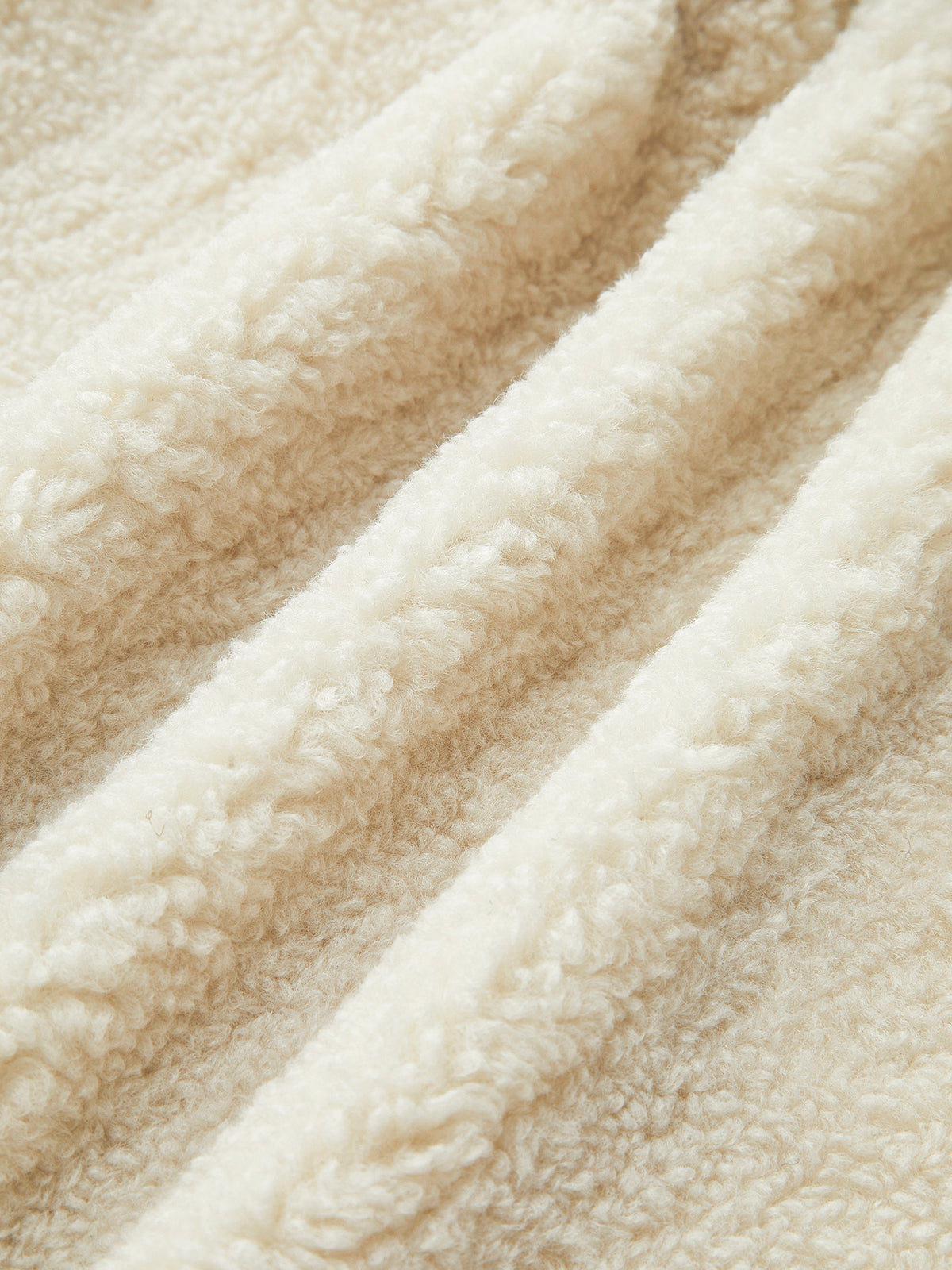 Beige Fleece-Stoff, weiche Textur, ideal für warme Kleidung und Decken, Nahaufnahme.